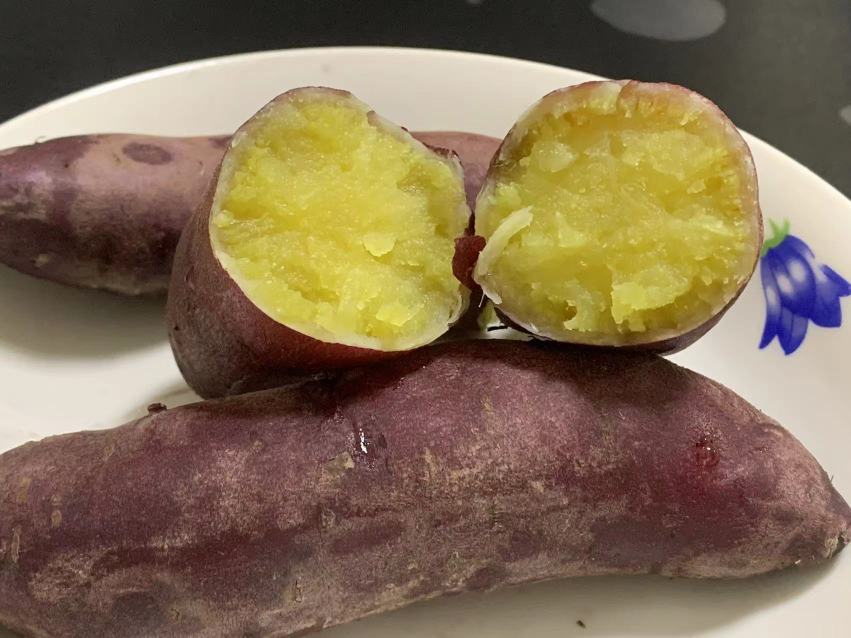 刚出炉的烟薯25号被横向剖开,橙红色薯肉饱满湿润,表面覆盖晶莹金黄色糖浆,部分呈滴落状,热气蒸腾,背景为不锈钢烤盘,突出其高温烘烤后的流蜜特性 烟薯25号切面流蜜特写