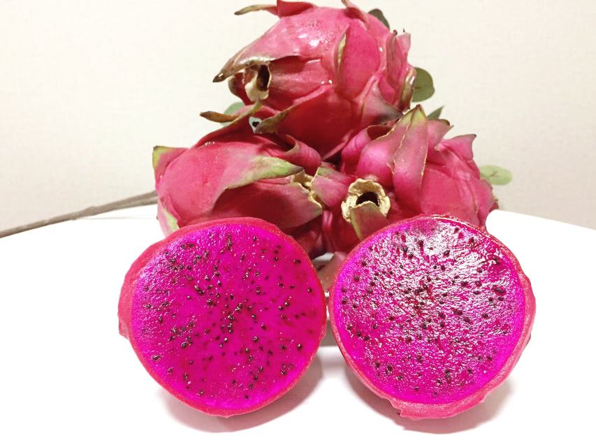 展示一颗完整的红心火龙果,果皮呈粉红色,果肉鲜红,切开后露出细腻的纹理 红心火龙果特写