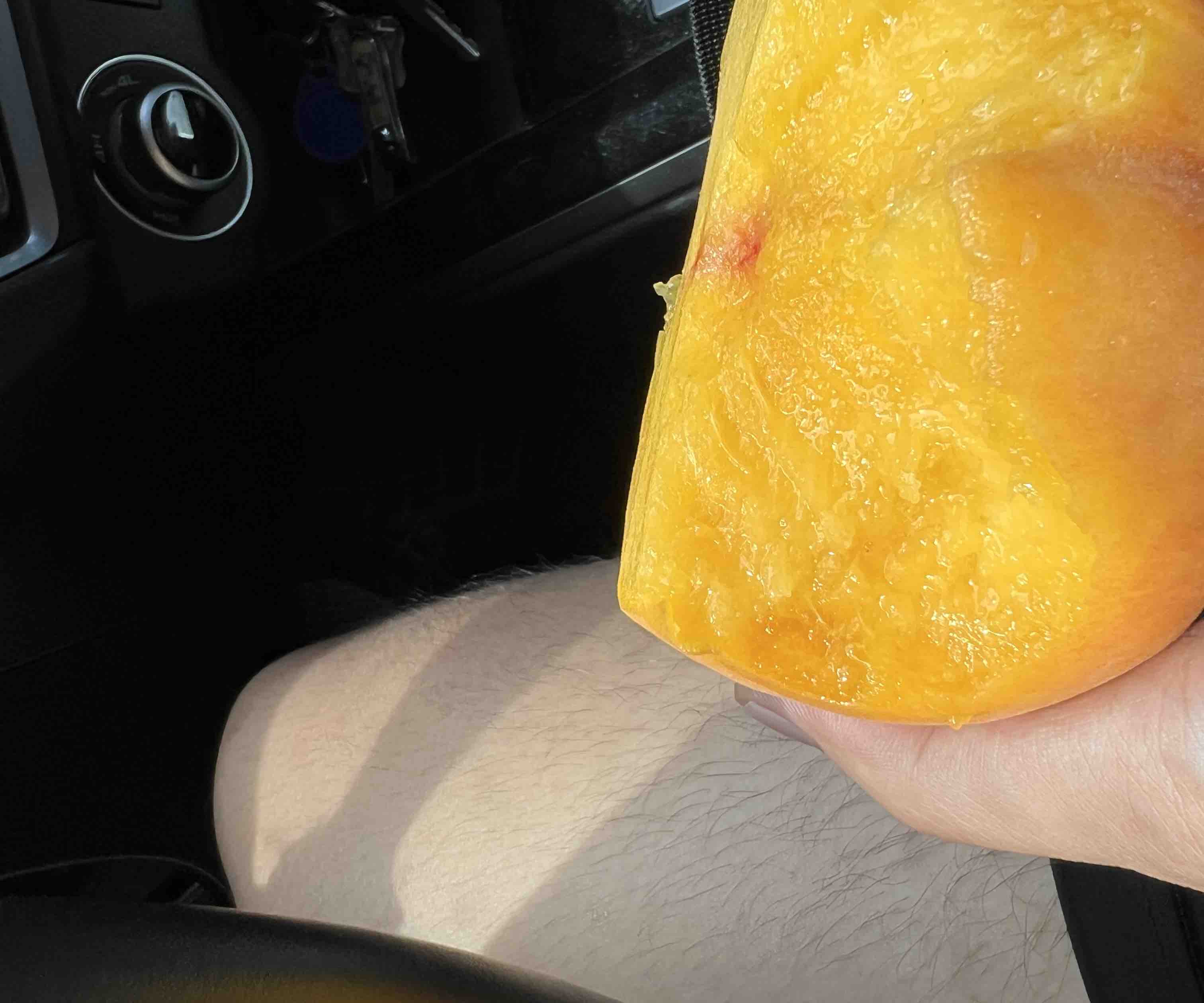 近距离拍摄一个新鲜黄桃的局部,清晰展现果皮上的细密果点、完整的绿色果梗、金黄色果皮光泽,无任何伤痕或斑点,背景虚化突出主体 新鲜黄桃细节特写