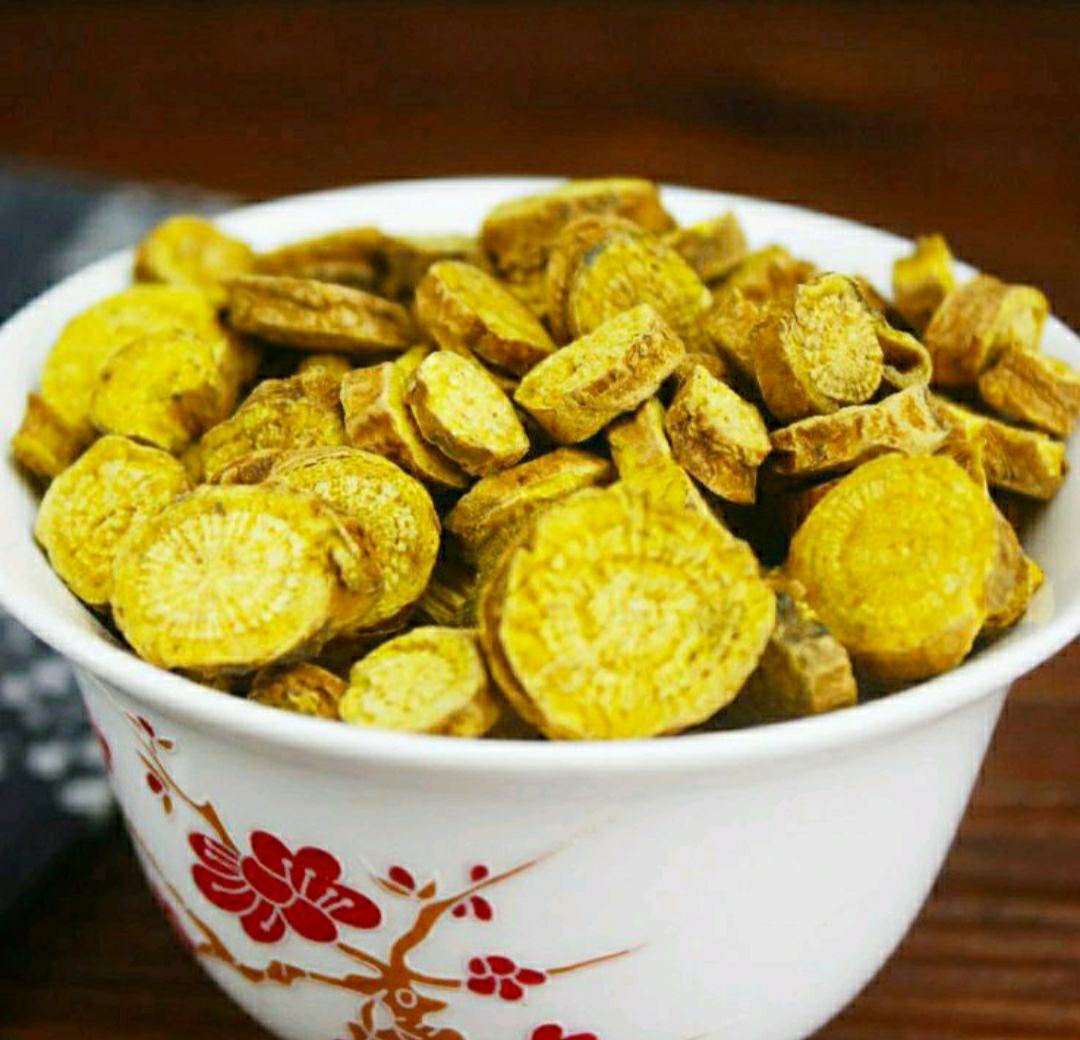 砂锅中盛放琥珀色清亮汤汁,浮着几片嫩滑猪肝和淡黄色黄芩片,汤面撒少量枸杞与葱花,背景为木质料理台与中药秤、玻璃罐装黄芩饮片 黄芩煲猪肝成品特写