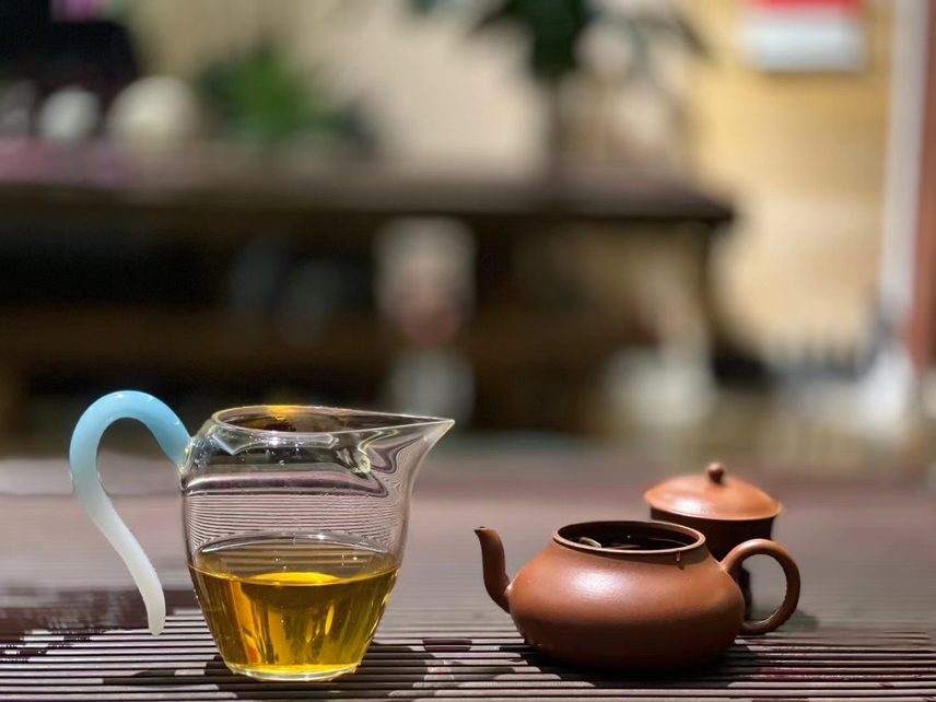 透明玻璃杯中泡着两颗焦枣,水面泛起淡淡金黄色,背景为木质桌面 池州焦枣泡水图