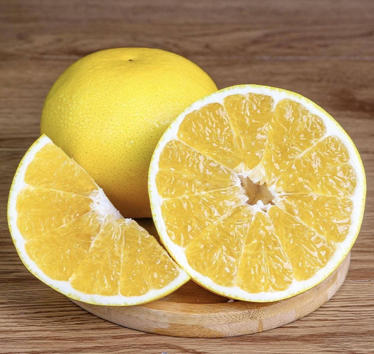 一颗新鲜的葡萄柚被切开,果肉饱满多汁,露出内部的果粒,背景为厨房台面 葡萄柚切开果肉多汁场景