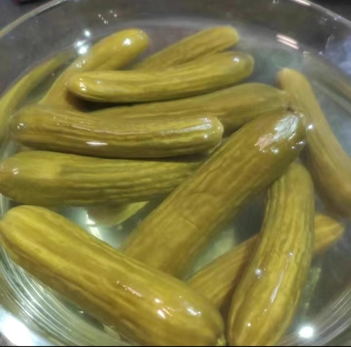 展示小黄瓜咸菜腌制过程中,小黄瓜被放入玻璃瓶中,倒入腌料汁,准备冷藏腌制 小黄瓜咸菜制作过程