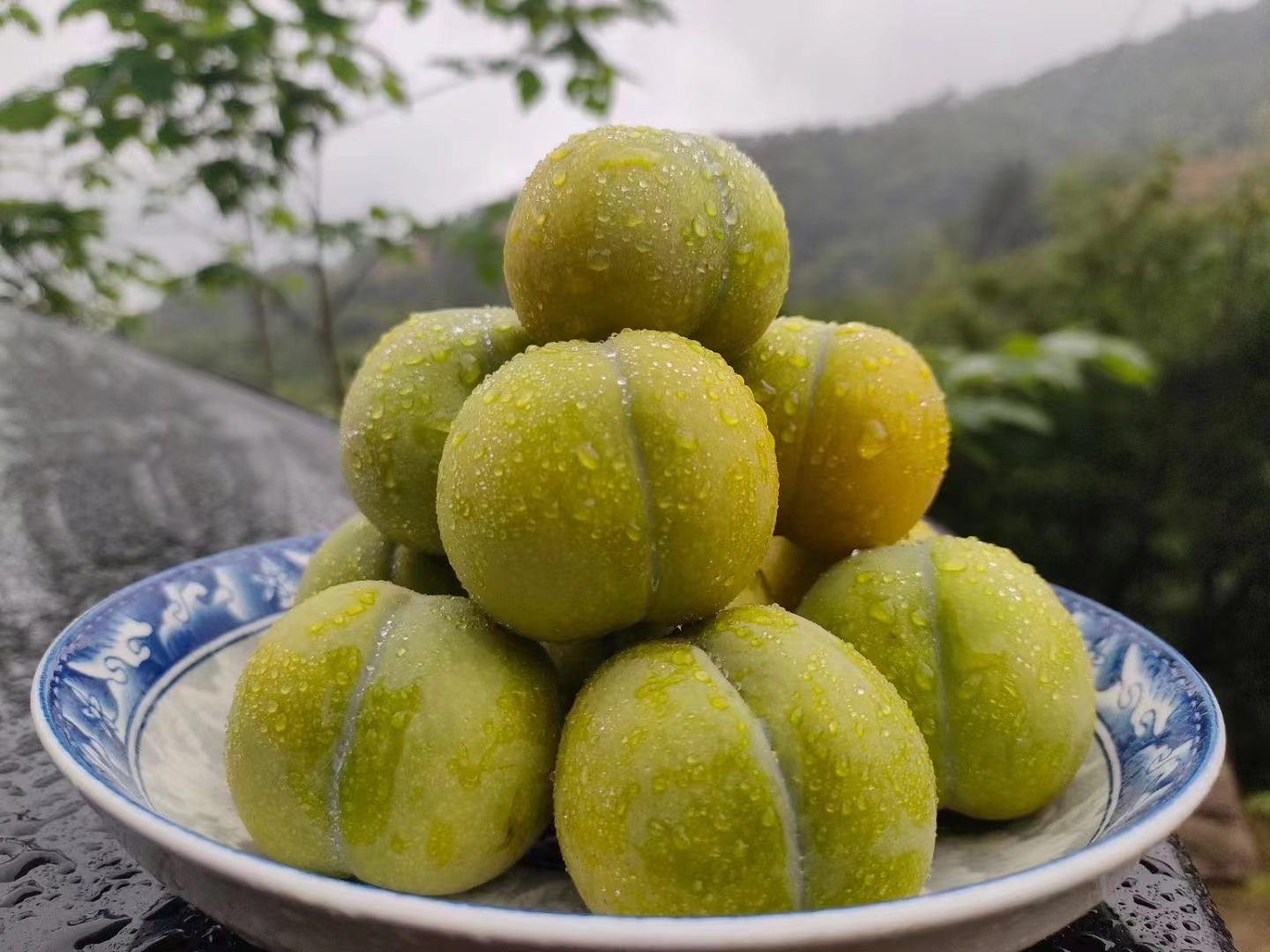 一颗被横向切开的蜂糖李,露出晶莹剔透的果肉,果核小而光滑,果肉厚实多汁,边缘有细微汁液渗出;背景为木质餐桌,旁边配有叉子和玻璃杯,突出其作为高端水果的食用场景 蜂糖李切开剖面图