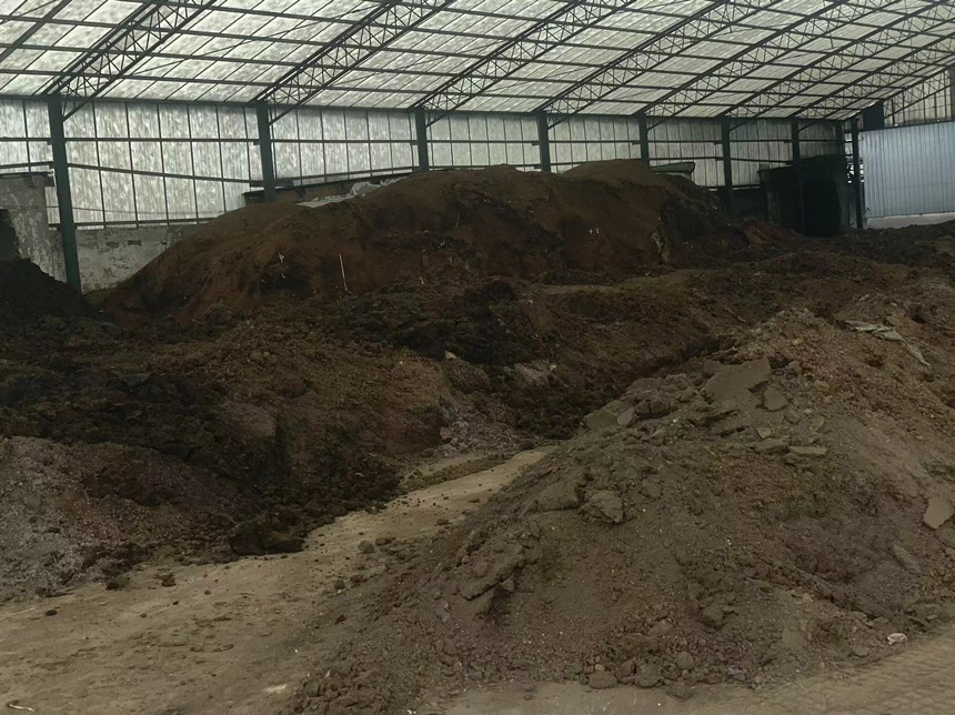 工作人员正在将平菇菌渣加入堆肥系统中进行发酵处理 平菇菌渣用于堆肥处理的场景