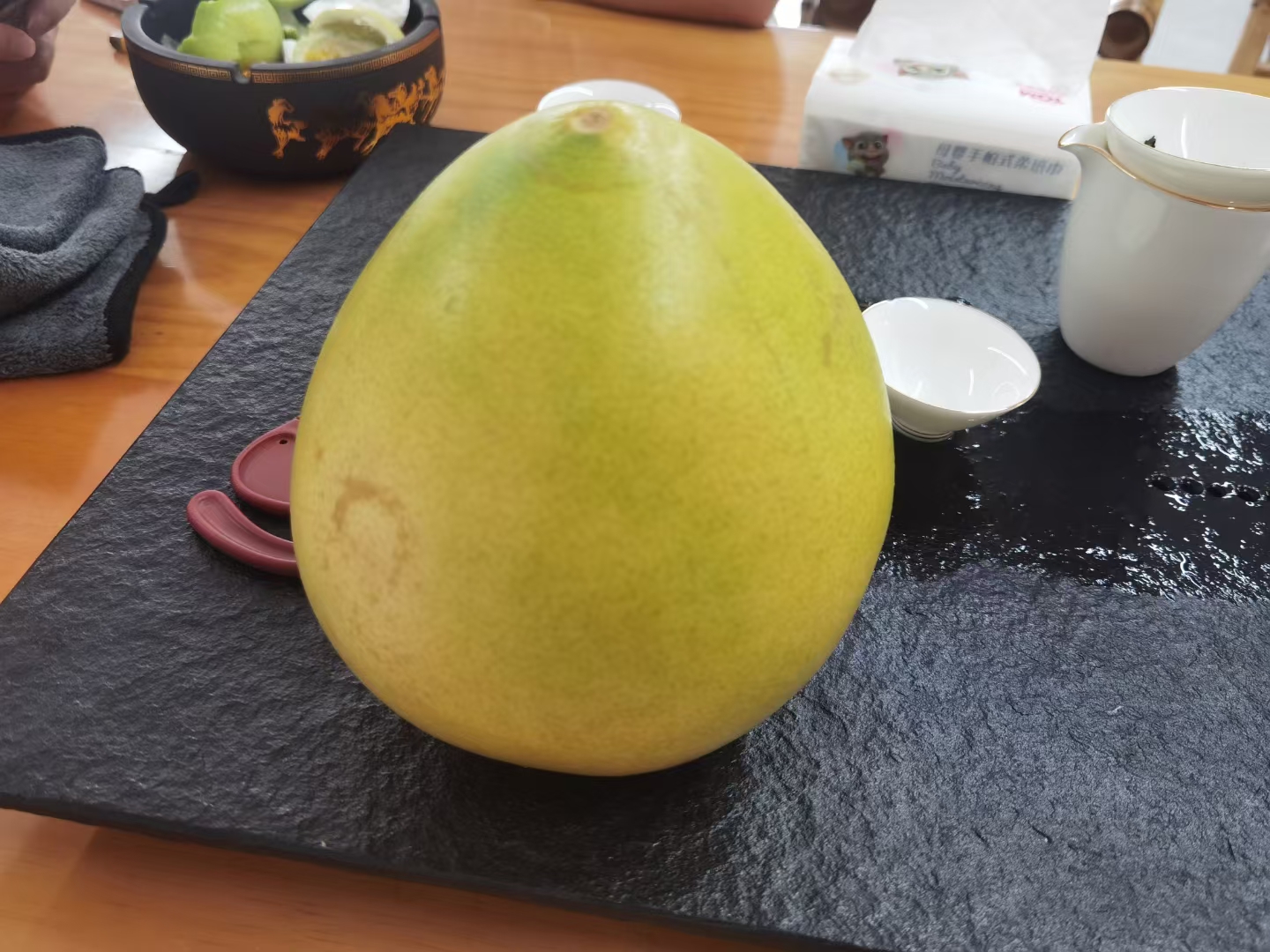 一杯晶莹剔透的葡萄柚红茶,搭配新鲜葡萄柚切片,背景为木质餐桌,营造出自然清新的氛围 葡萄柚红茶成品图