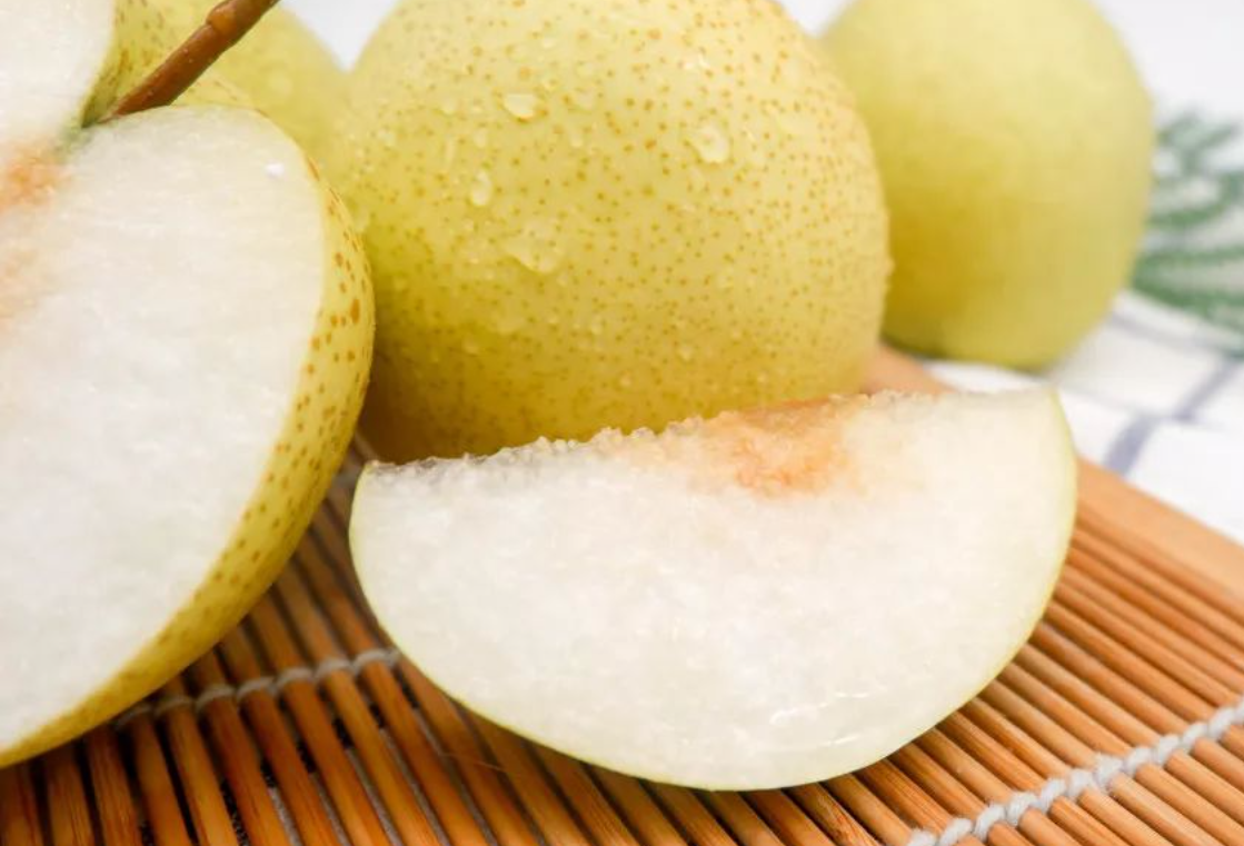 一颗切开的红香酥梨特写,左侧为完整果实,红褐色外皮带有细小斑点,右侧为剖面,露出洁白晶莹的果肉,质地细腻无渣,果汁清晰可见,果心小巧,背景为木质砧板和绿叶衬托,整体画面清新自然 红香酥梨特写展示图