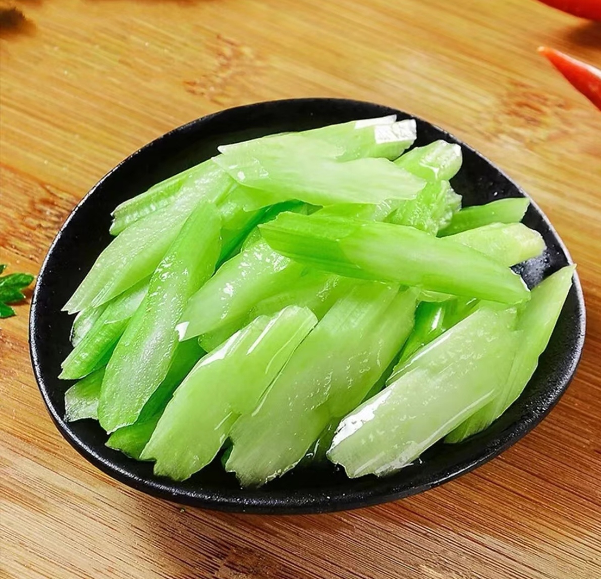 现代厨房中的毛芹应用：青瓷碗盛放毛芹炒香干，色泽碧绿油亮，香干褐黄微焦，点缀红椒丝与白芝麻，旁边摆放洗净待用的带毛鲜嫩毛芹段，台面木质纹理自然温馨